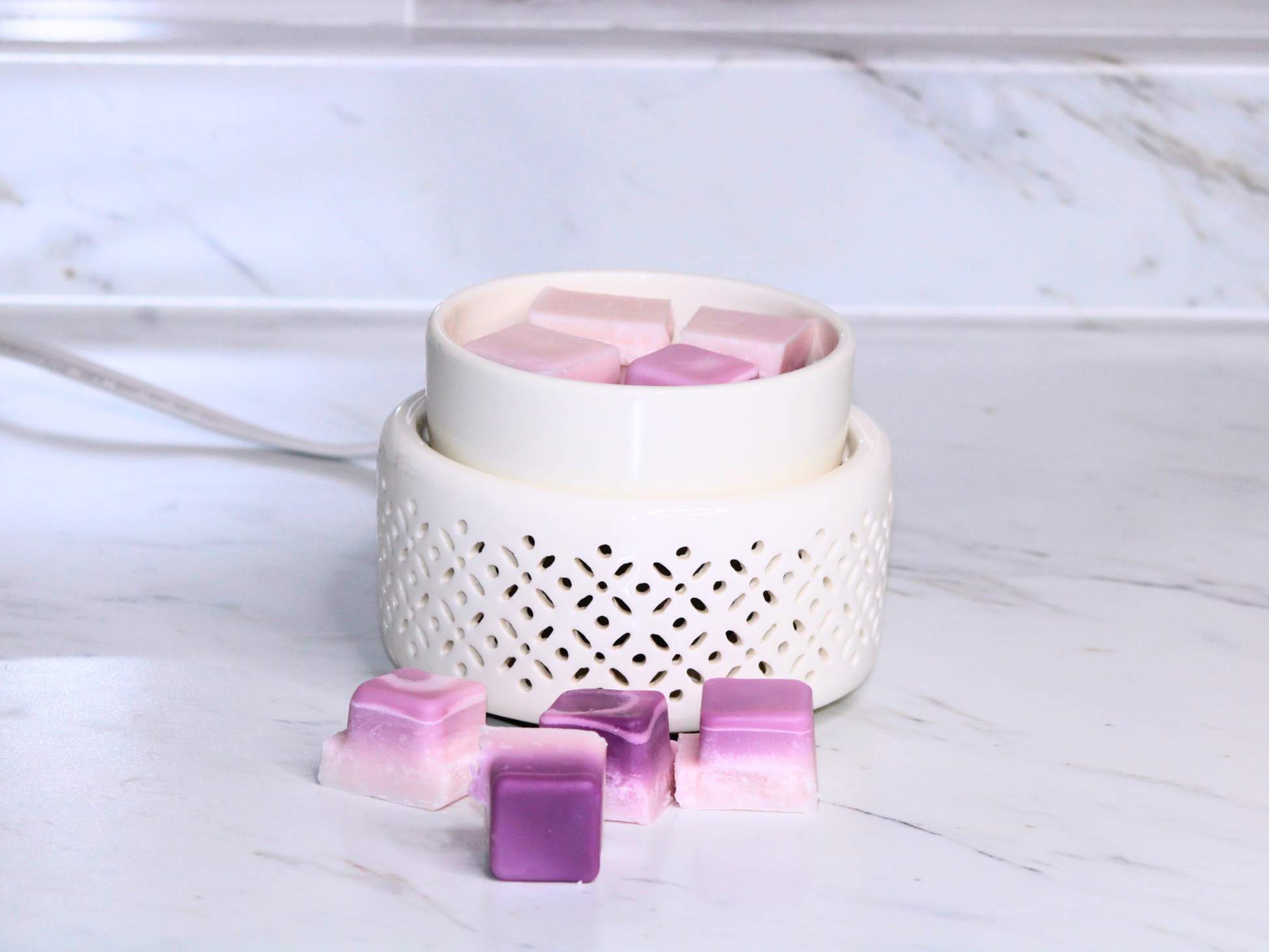White wax warmer with lavender and purple wax cubes on a marble surface