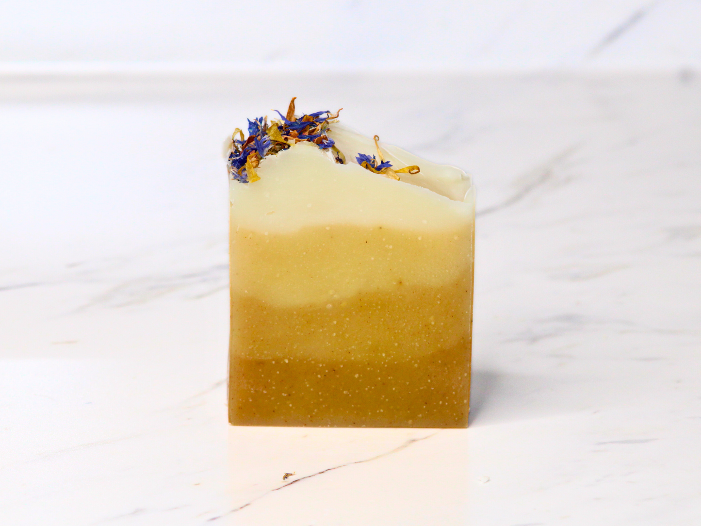 A bar of soap with dried flowers on a marble surface