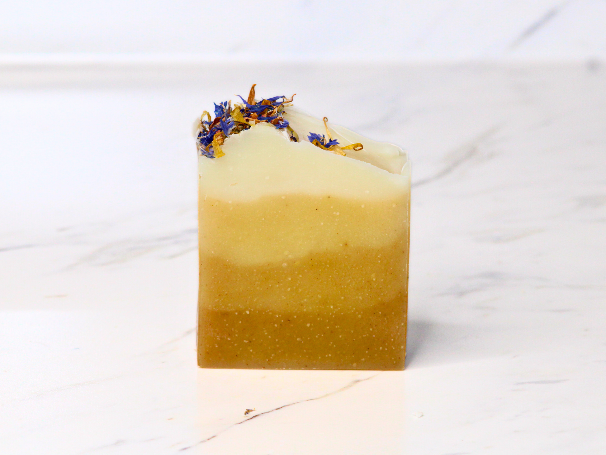 A bar of soap with dried flowers on a marble surface