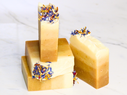 Four bars of soap with dried flowers on a marble surface